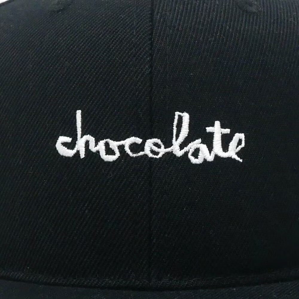Black cap with 'chocolate' embroidered in white on a close-up view