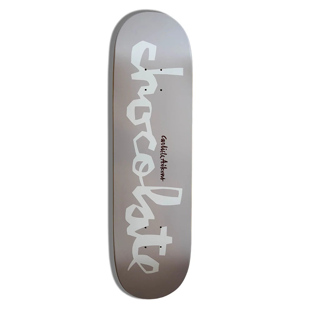 A skateboard deck with a metallic silver gradient background, featuring the word 'chocolate' in large white script and 'can't wait' in smaller black text.