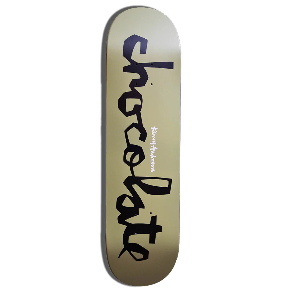 A skateboard deck with a metallic gold background and the word 'chocolate' printed vertically in black script, with 'Kenny anderson' in smaller white text, shown on a plain white background.