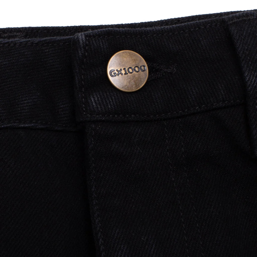 Close-up of black pants with a button featuring 'GX1000' branding on a white background.
