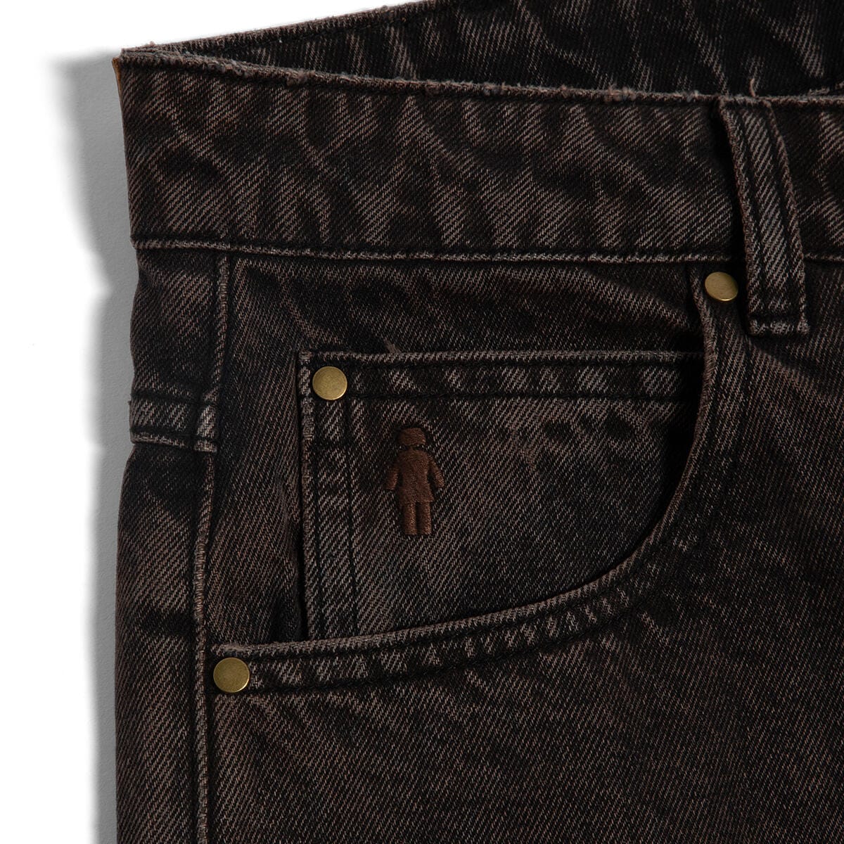 Close-up of dark denim jeans with stitching details on a light gray background