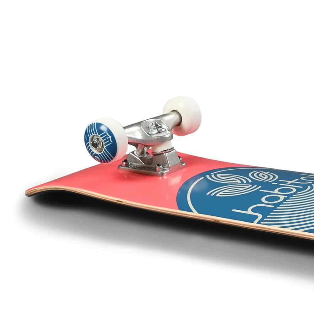 Close-up of a skateboard with red deck, blue graphic, and white trucks on a white background