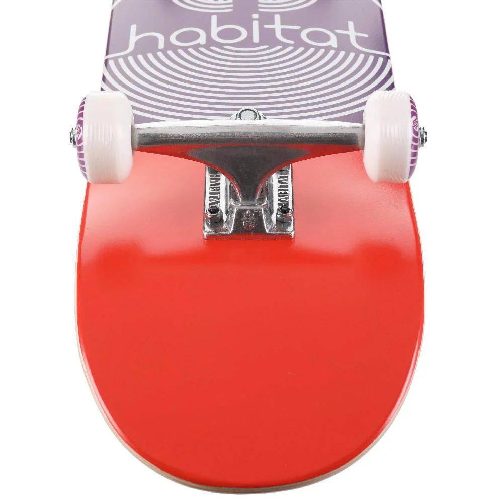 Close-up of a red skateboard with 'habitat' branding on a white background