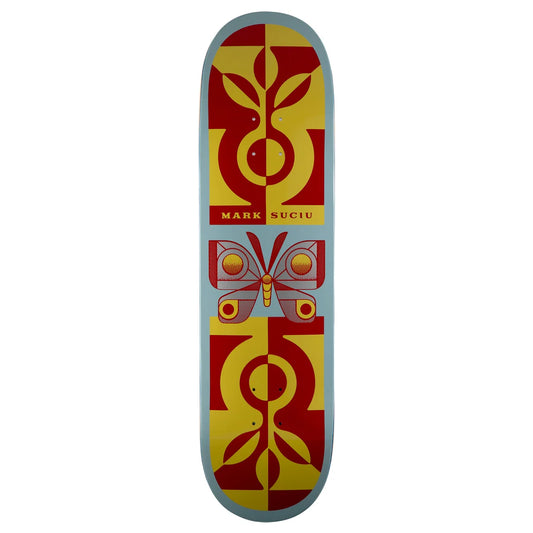 A skateboard deck featuring a symmetrical graphic design with a butterfly in the center and abstract plant motifs at the top and bottom. The design is split into red and yellow sections on a light blue background, with the text 'MARK SUCIU' printed in the center.