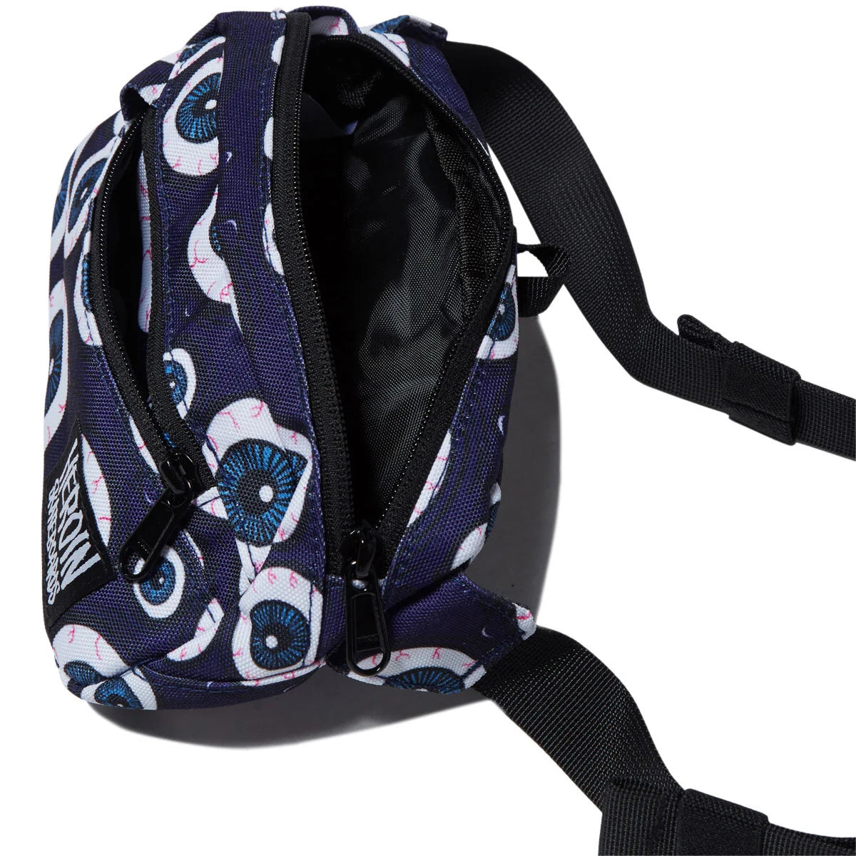 A close-up of a small crossbody bag with a dark navy blue base, featuring a white and blue eyeball print, black zippers, and a black adjustable strap on a white background.