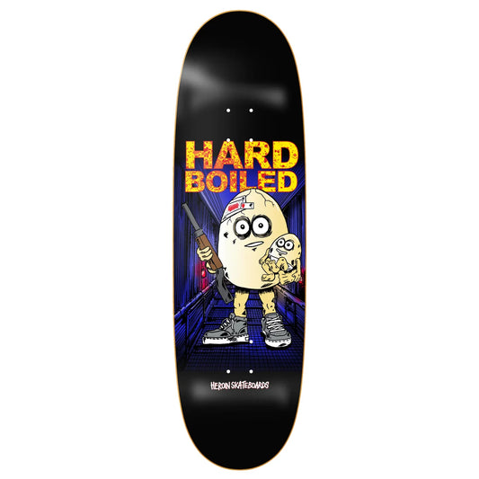 A skateboard deck shown vertically against a plain white background. The deck has a black base with a colorful graphic featuring the text 'HARD BOILED' in yellow and orange, and a cartoon character holding a gun and a phone.