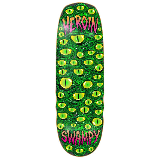 A skateboard deck featuring a green alligator pattern with yellow eyes and pink text reading 'HEROIN' at the top and 'SWAMPY' at the bottom, shown against a plain white background.