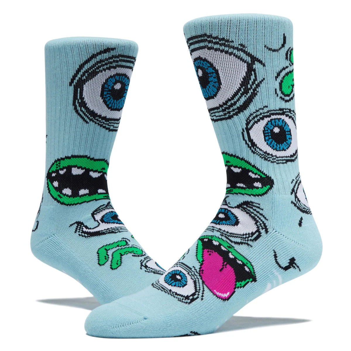 A pair of light blue crew socks featuring a bold, graphic cartoon monster face pattern with blue eyes, green teeth, and a pink tongue, displayed on a clean white background.