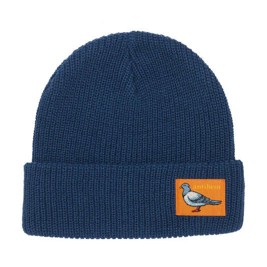 A navy blue ribbed knit beanie hat featuring a folded cuff with an orange rectangular patch displaying a pigeon illustration and the text 'antihero'.