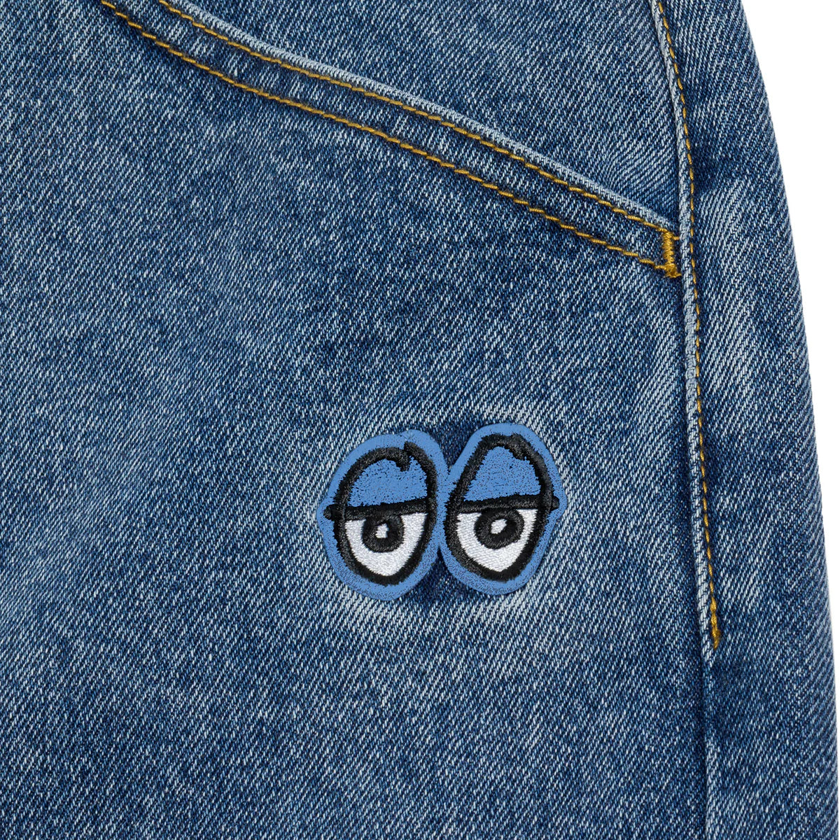 Blue denim fabric with a patch of cartoonish eyes on a white background