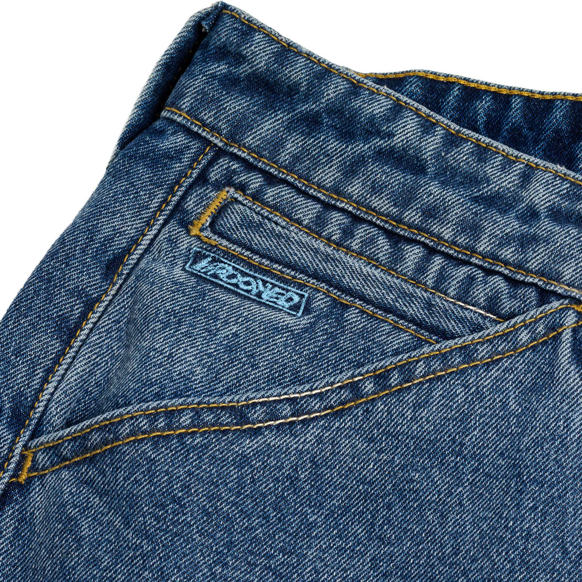 Close-up of a blue denim pocket with a brand label on a white background
