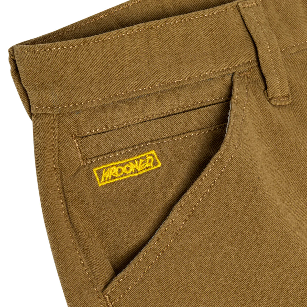 Close-up of brown pants with a yellow label on a white background