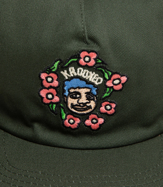 Embroidered patch on a green cap with floral design and 'KROOKED' text.