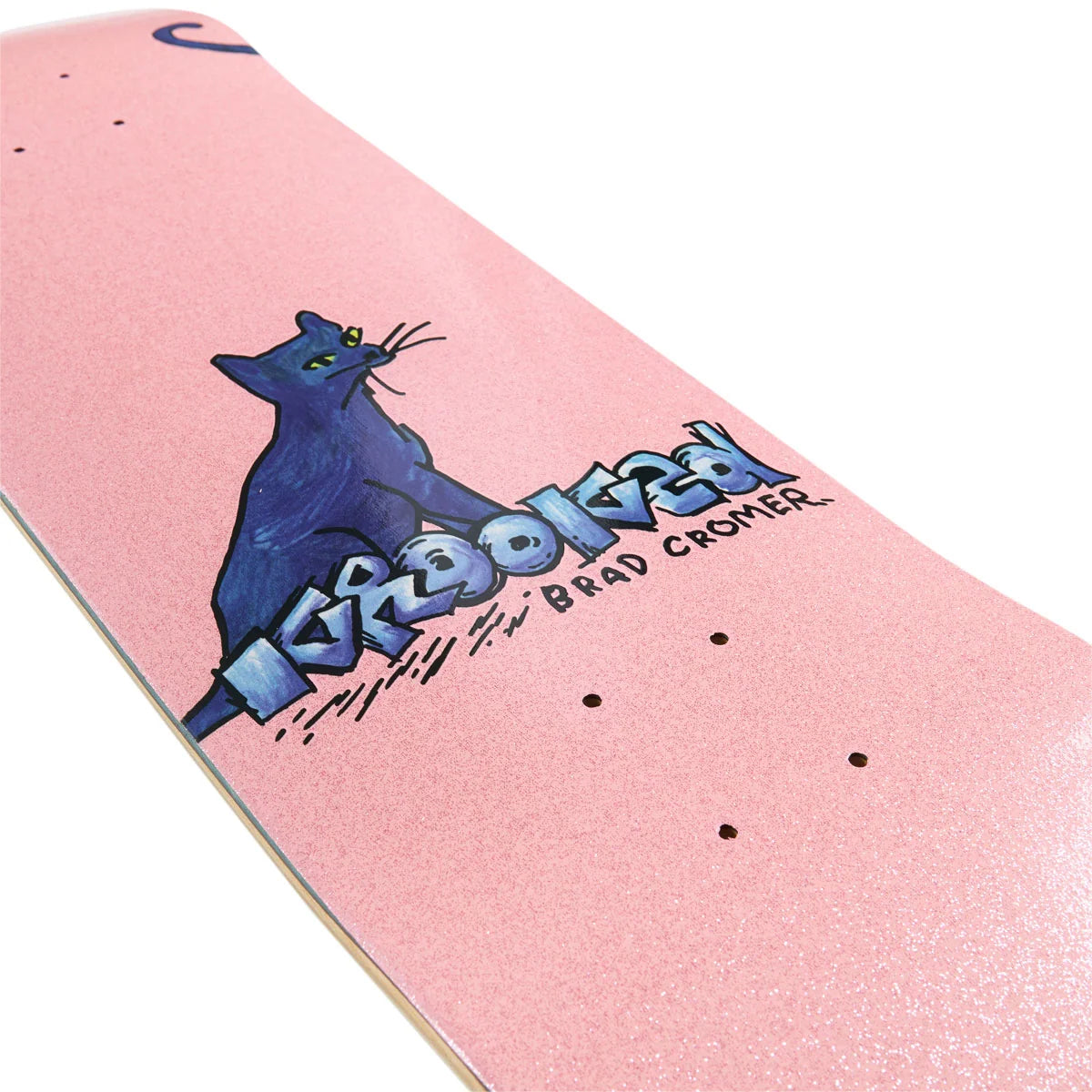 A close-up of a skateboard deck featuring a pink glitter finish, a blue cat graphic, and the text 'krooked' and 'Brad Cromer'.