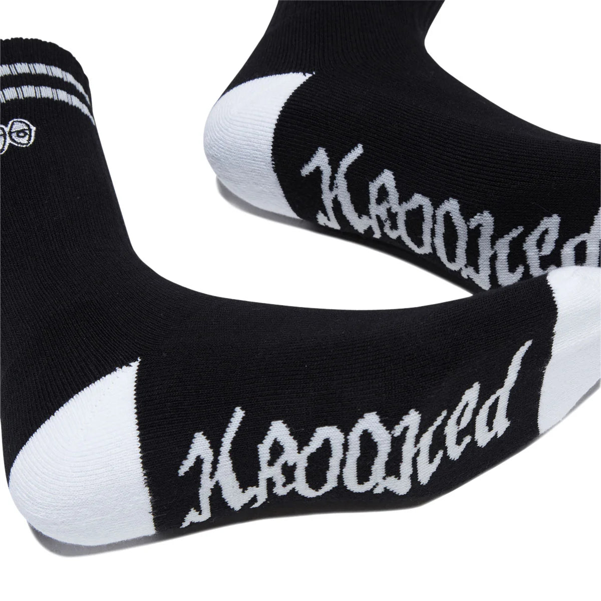 Black crew socks with white toe and heel sections, featuring the word 'krooked' in a white gothic font across the sole, displayed on a white background.