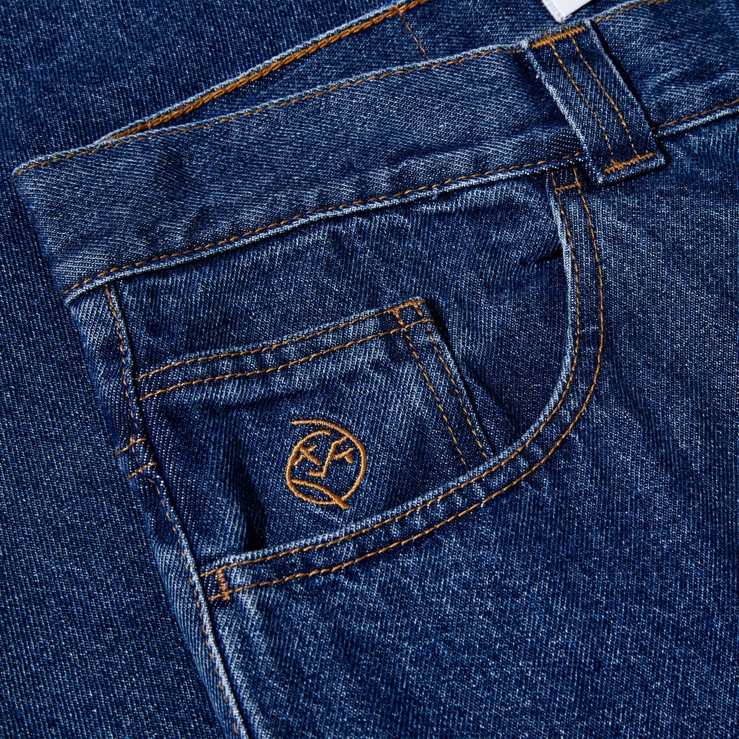 Close-up of blue denim jeans with a brand logo on the pocket.