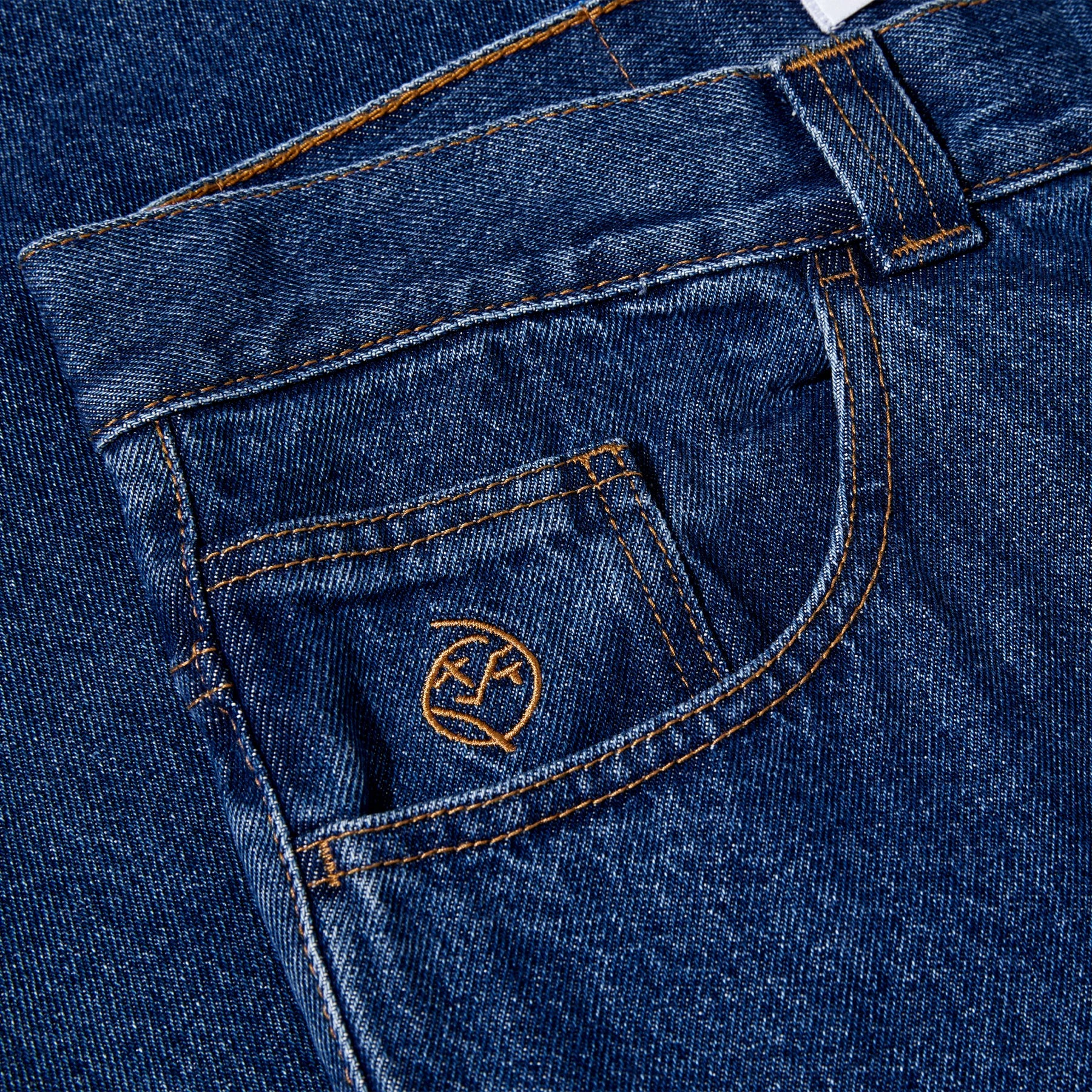 Close-up of blue denim jeans with a brand logo on the pocket.