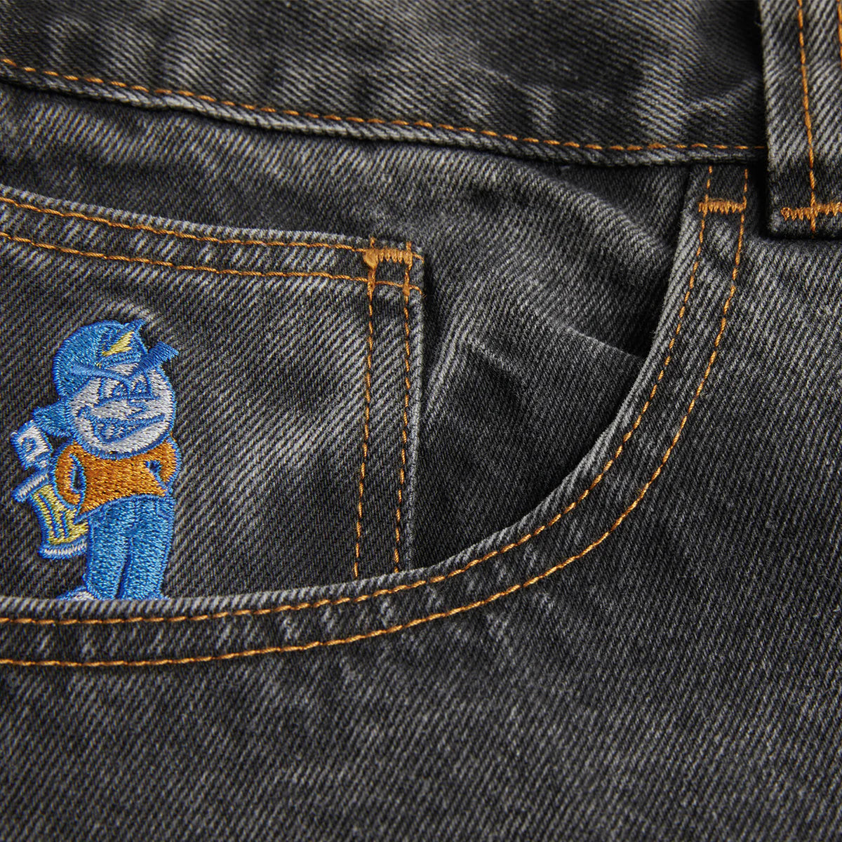 Embroidered character on a pocket of dark denim fabric