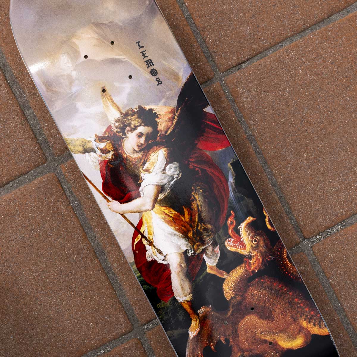 Skateboard with angel and dragon design on a tiled floor