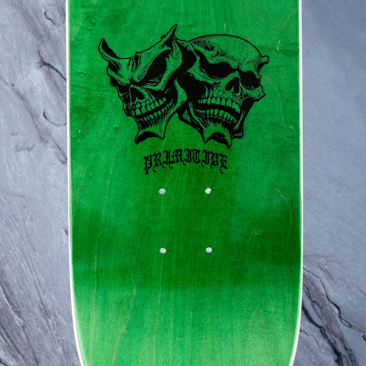 A green skateboard deck shown from the underside, featuring a black graphic of two skulls with horns and the word 'PREMIERE' printed below them. The deck is photographed flat against a textured gray background.
