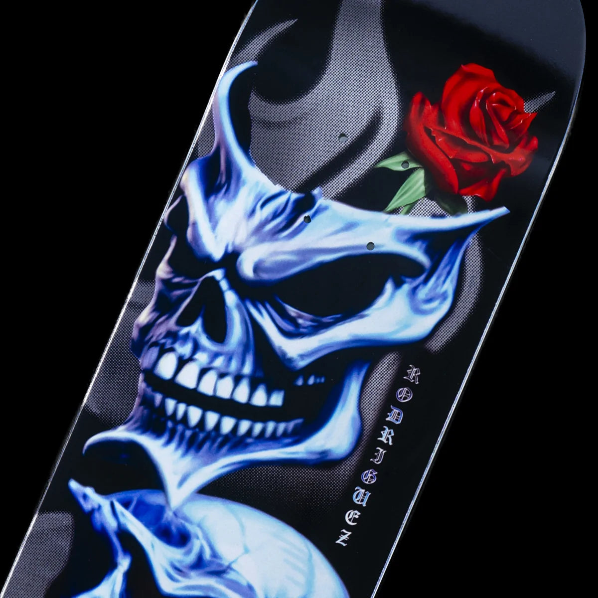 A close-up of a skateboard deck featuring a large blue and white skull graphic, a red rose near the top right, and the brand name 'Skate Chix' printed vertically in white.