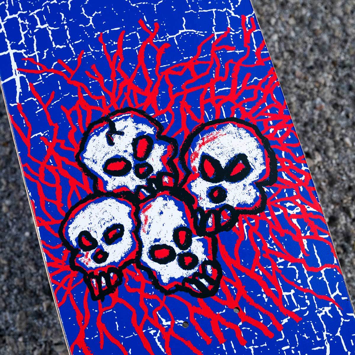 Skateboard deck with skull design on a blue and red cracked pattern