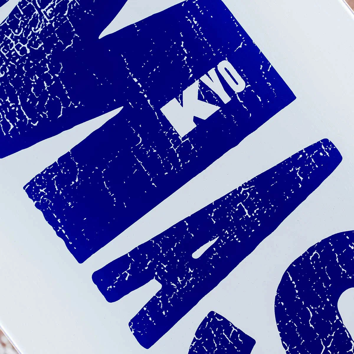 A close-up of a white surface with large distressed blue lettering. The letters are partially cropped, and the visible text includes 'KYO'.