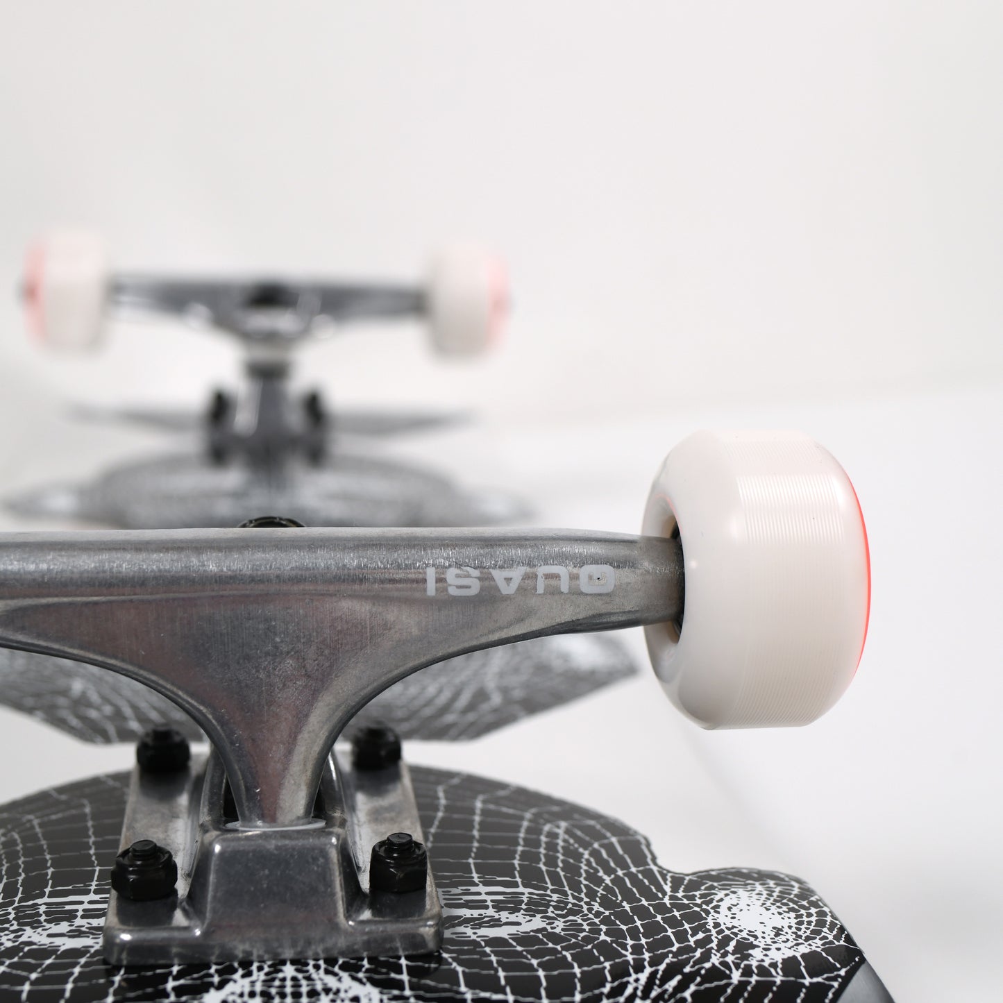 Close-up of a skateboard with a white wheel and spider web design on the deck.
