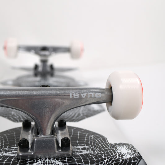 Close-up of a skateboard with a white wheel and spider web design on the deck.