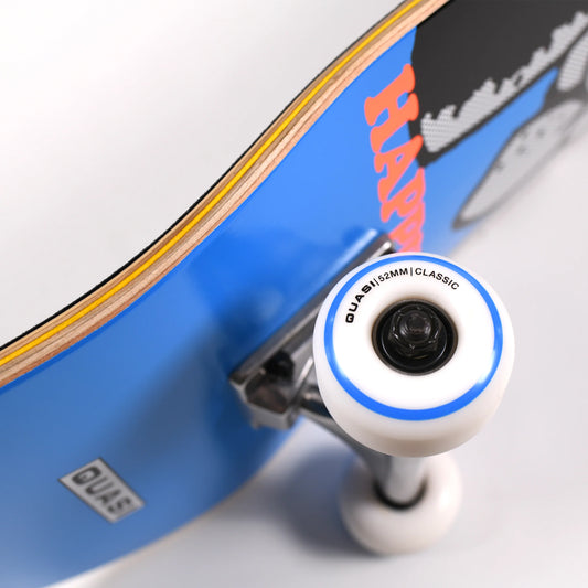 Close-up of a skateboard wheel and truck assembly with a blue deck, white wheel, blue ring, and visible quasi branding on the deck.