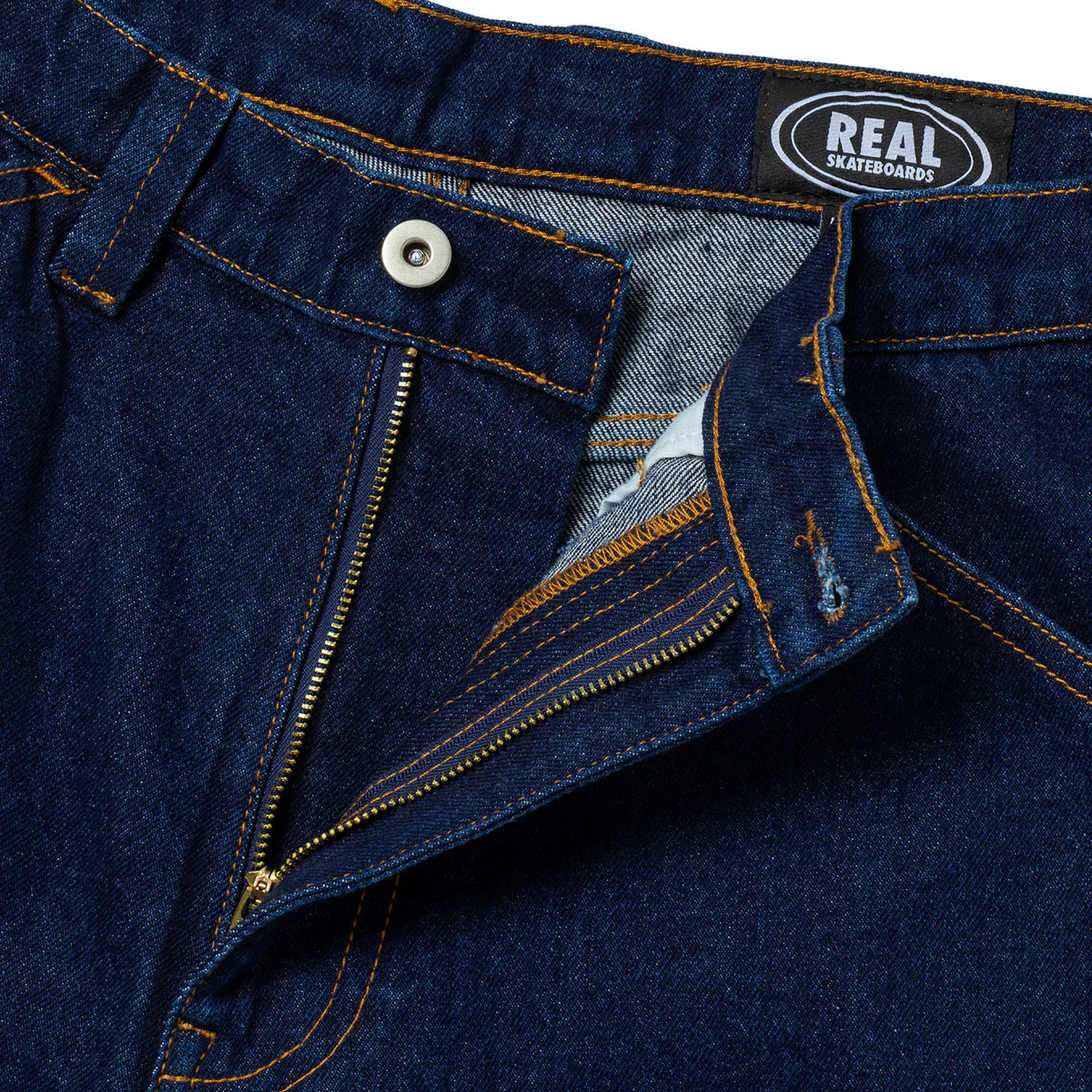 Close-up of blue jeans with a visible 'Real Skateboards' label.