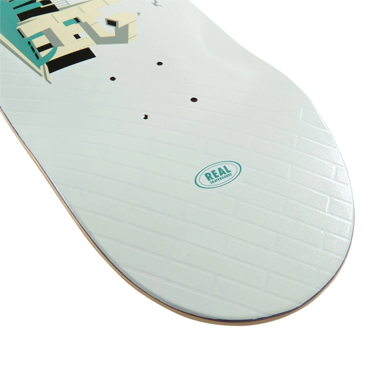 Close-up of a skateboard deck showing the underside with a white brick-patterned graphic, a teal and cream graphic in the top-left, and a circular 'REAL SKATEBOARD' logo near the center.