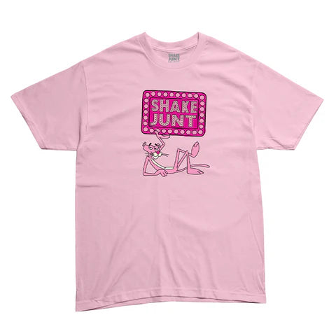 A light pink short-sleeve t-shirt featuring a graphic of the Pink Panther holding a pink marquee sign that reads 'SHAKE JUNT' in white letters.