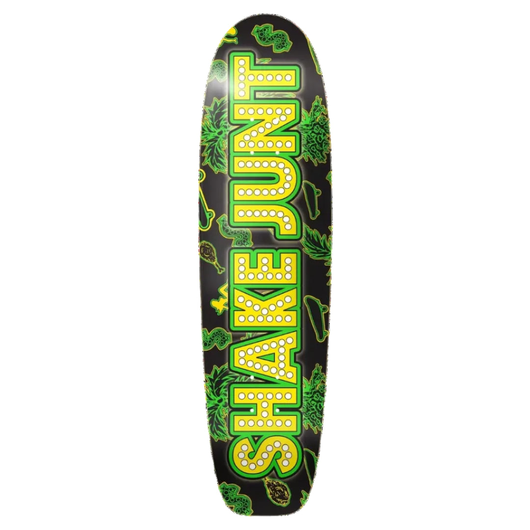 A skateboard deck featuring a black background with a large vertical 'SHAKE JUNT' logo in yellow letters outlined in green, decorated with green cannabis leaf illustrations.