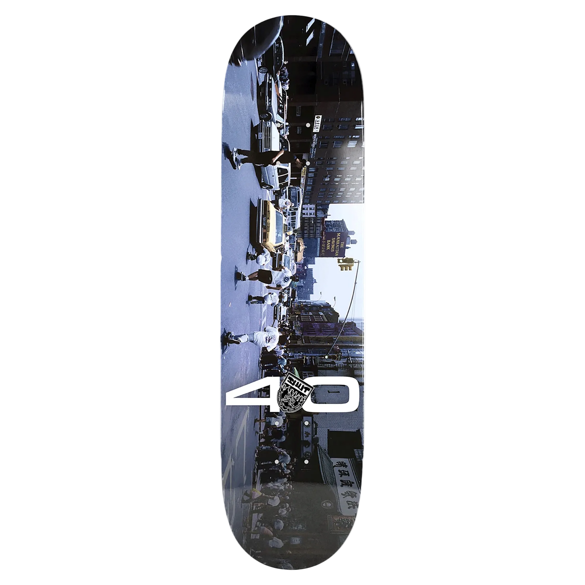 A skateboard deck featuring a full-length photographic print of a city street scene with pedestrians and buildings, overlaid with a large white '40' graphic and a circular 'Skate Shop' logo near the bottom center.