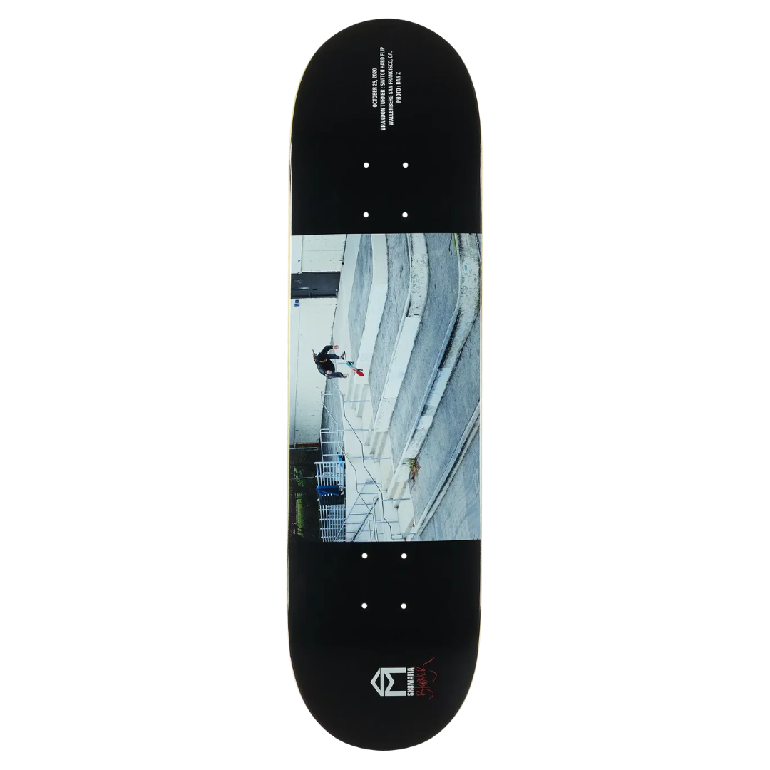 A black skateboard deck featuring a large rectangular graphic print of a skateboarder in a skatepark on the underside, with white text and a small red/black logo near the bottom.
