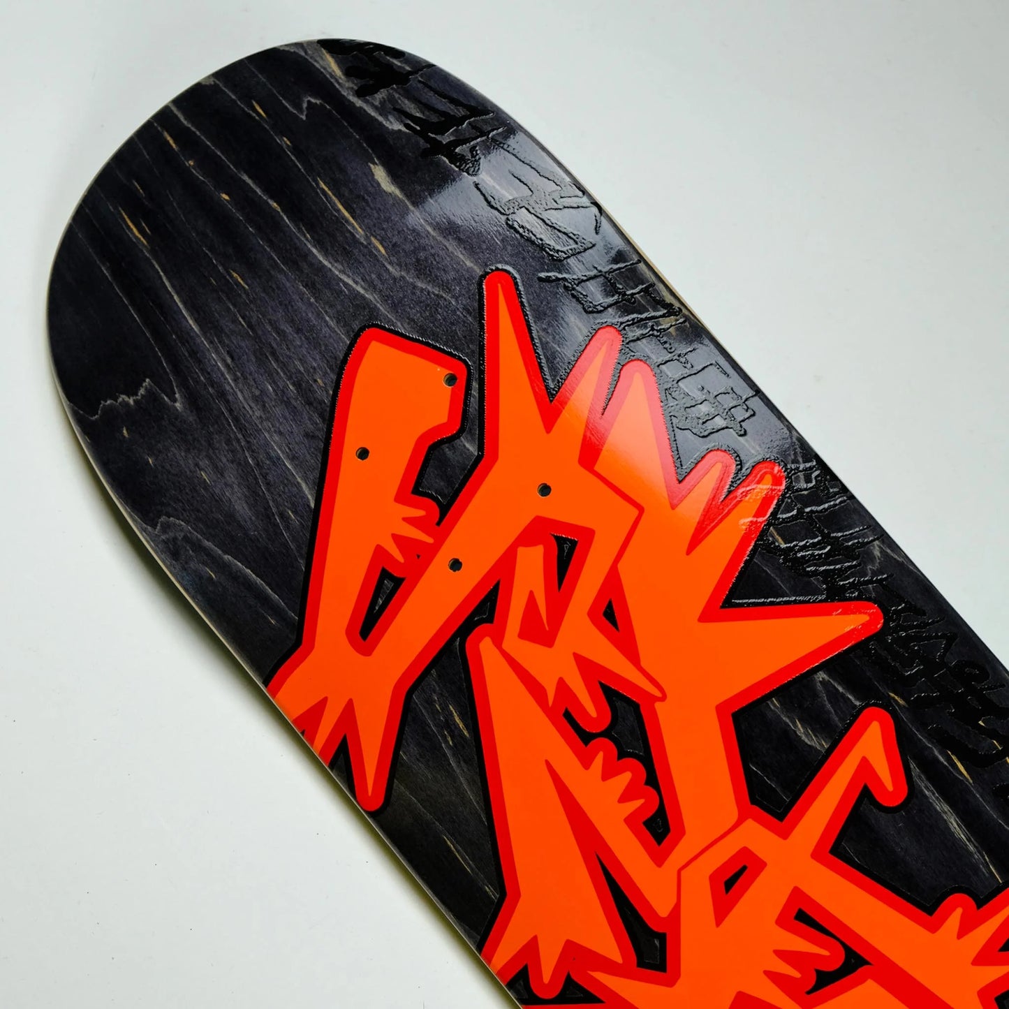 Skateboard deck with orange logo on a black background