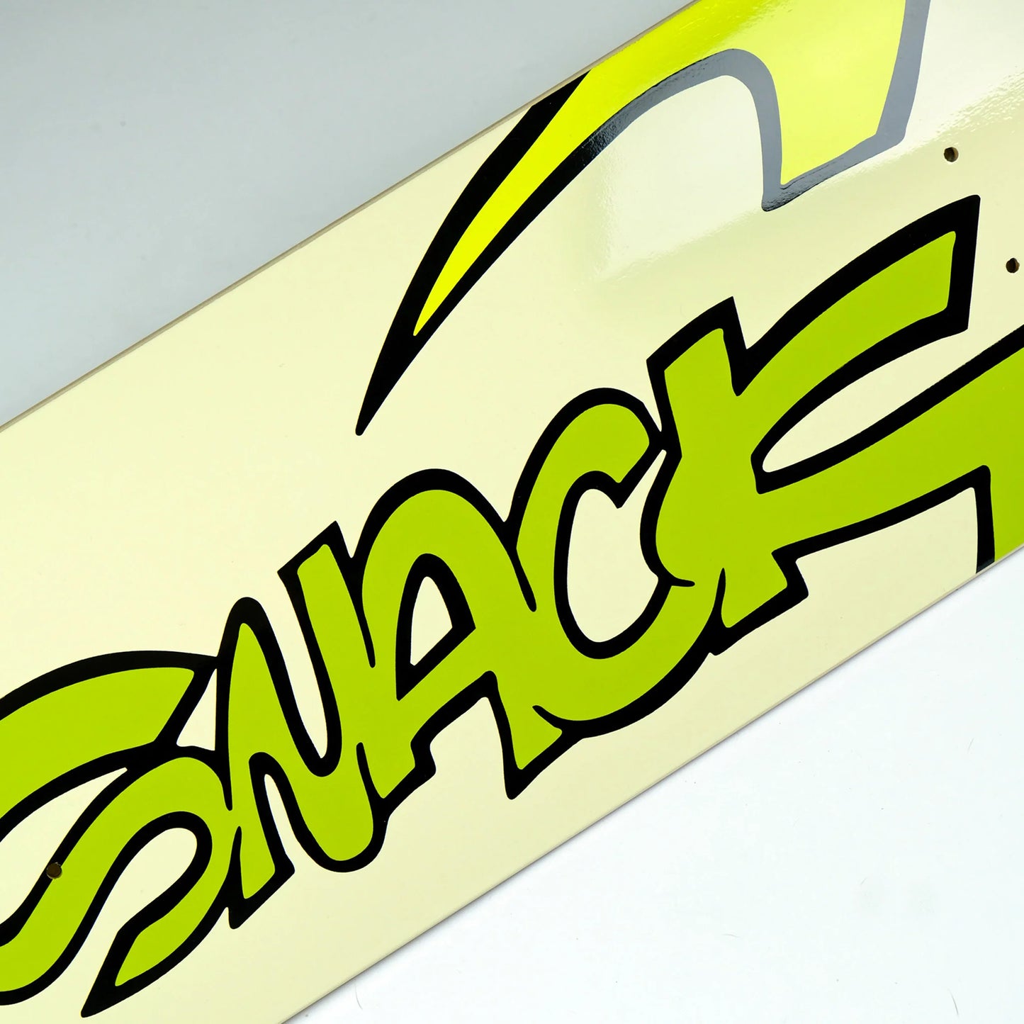 Close-up of a skateboard with a green 'Snack' logo on a light background