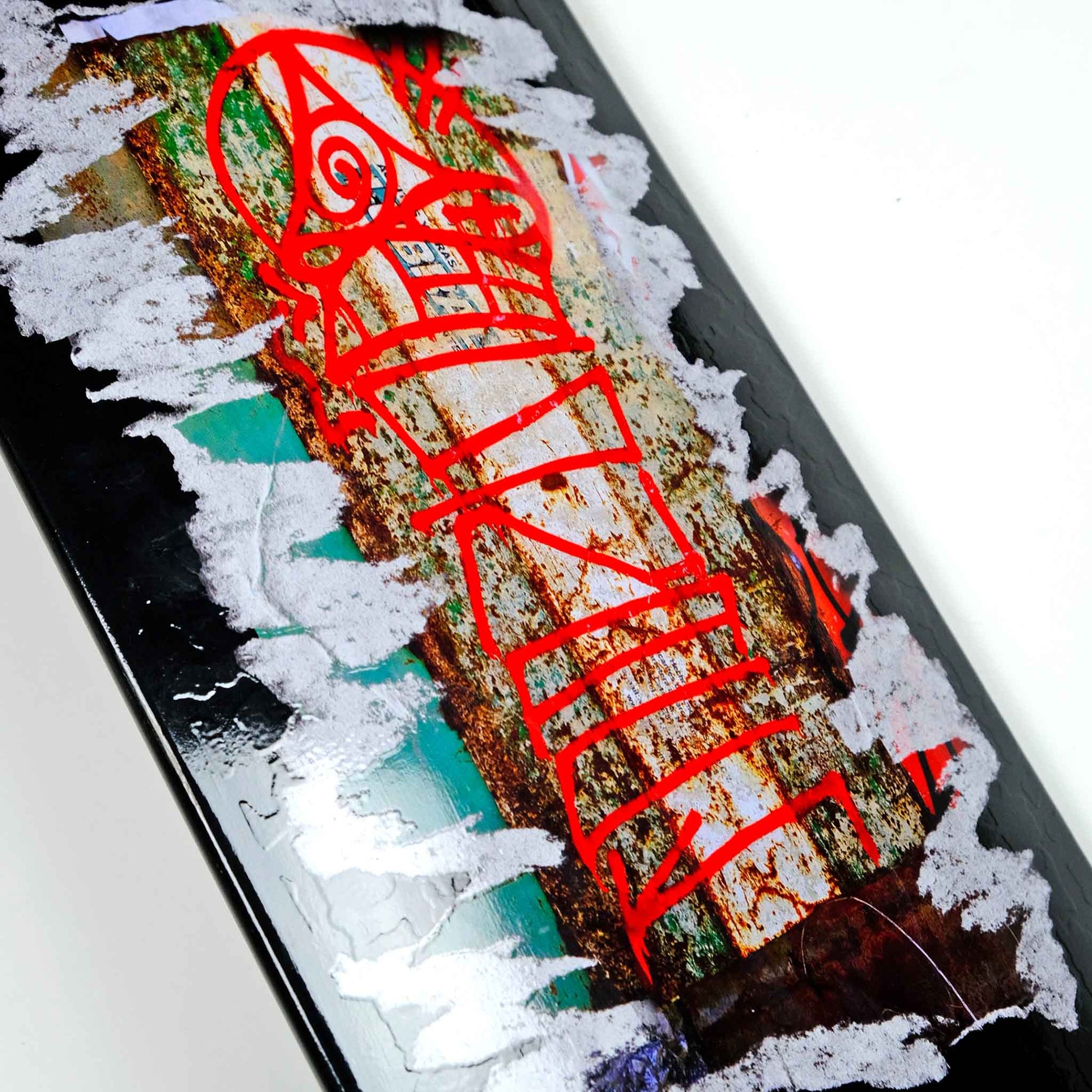 Close-up of a skateboard with red graphics on a white background