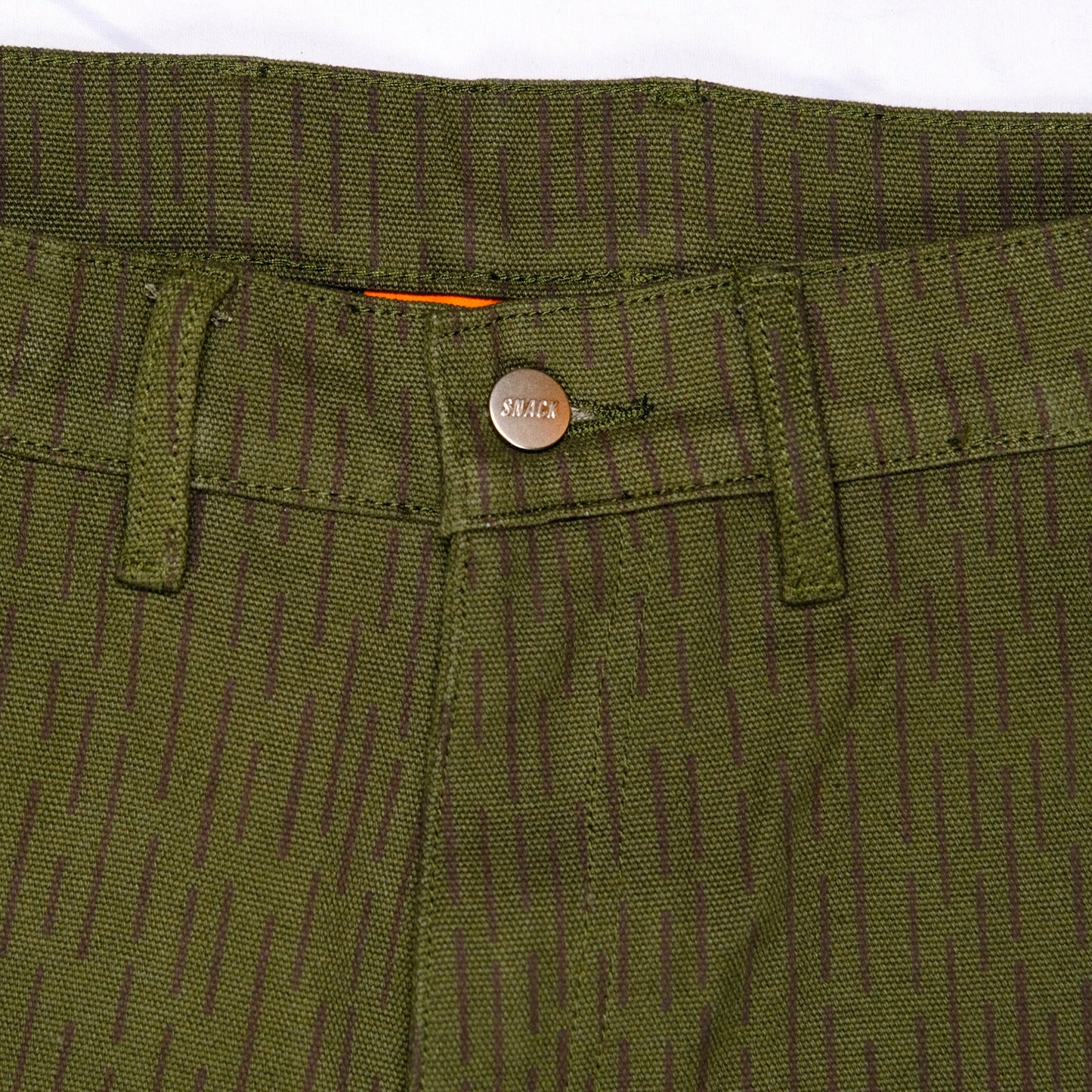 Close-up of green pants with a brand logo on the pocket