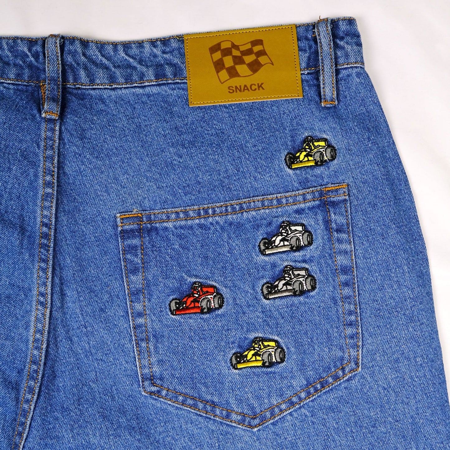 Blue denim pocket with race car pins and a yellow patch on a white background