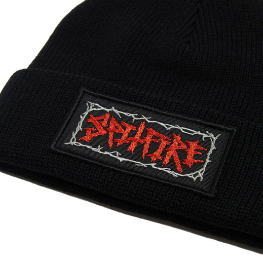 Close-up of a black ribbed knit beanie with a rectangular embroidered patch on the cuff. The patch features the word 'spitfire' in red stylized lettering outlined with white barbed wire on a black background.