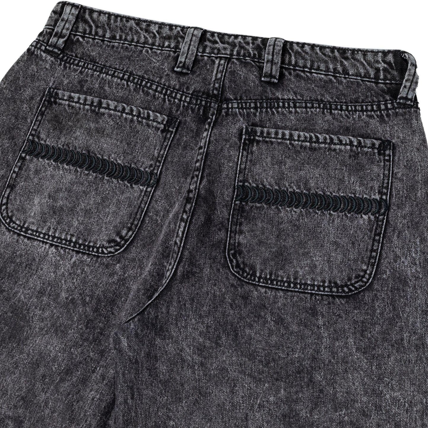 Close-up of black denim jeans with a focus on the back pocket.