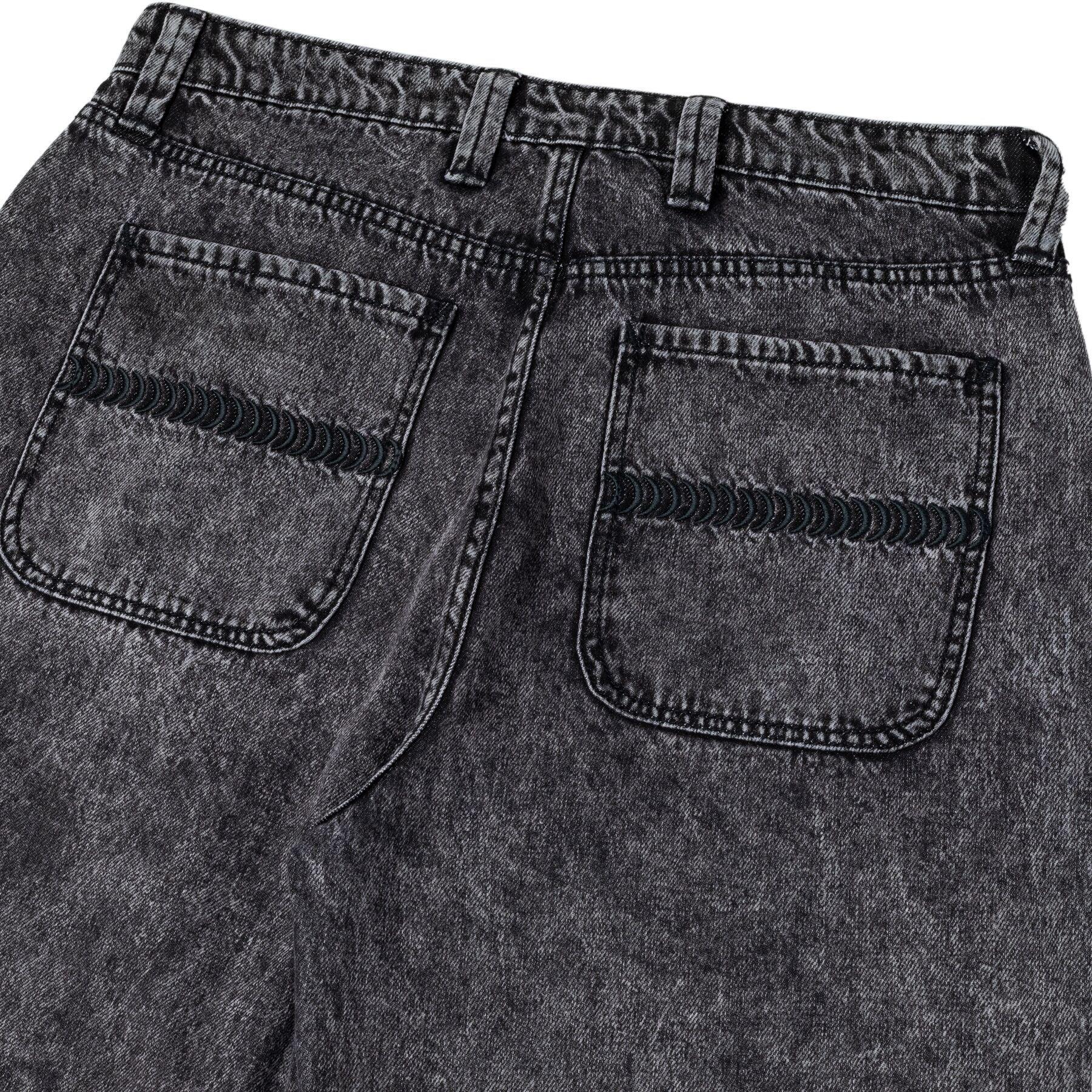 Close-up of black denim jeans with a focus on the back pocket.