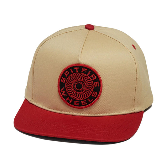 A beige and red snapback cap featuring a circular red and black 'SPITFIRE WHEELS' patch on the front, set against a plain white background.