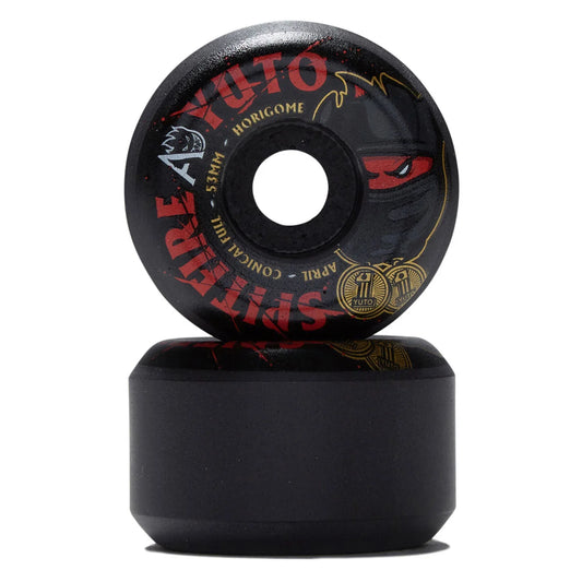A pair of black skateboard wheels stacked vertically on a white background. The top wheel features red and gold graphics with the text 'YUTO', 'HORIgOME', 'SPIT FIRE', 'APRIL', and 'CONICAL FILL'.