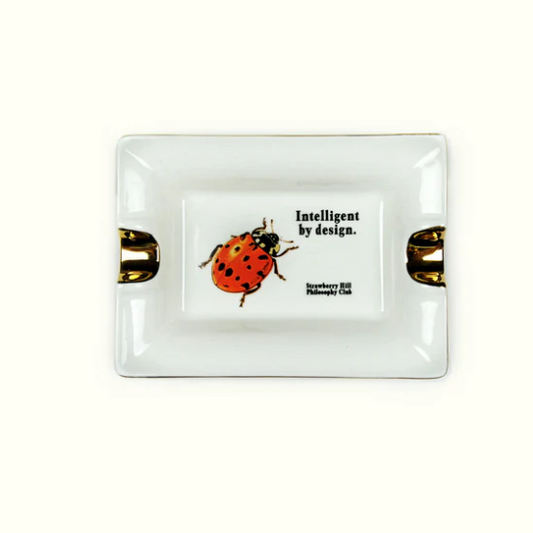 White ceramic ashtray with a ladybug illustration and text on a white background