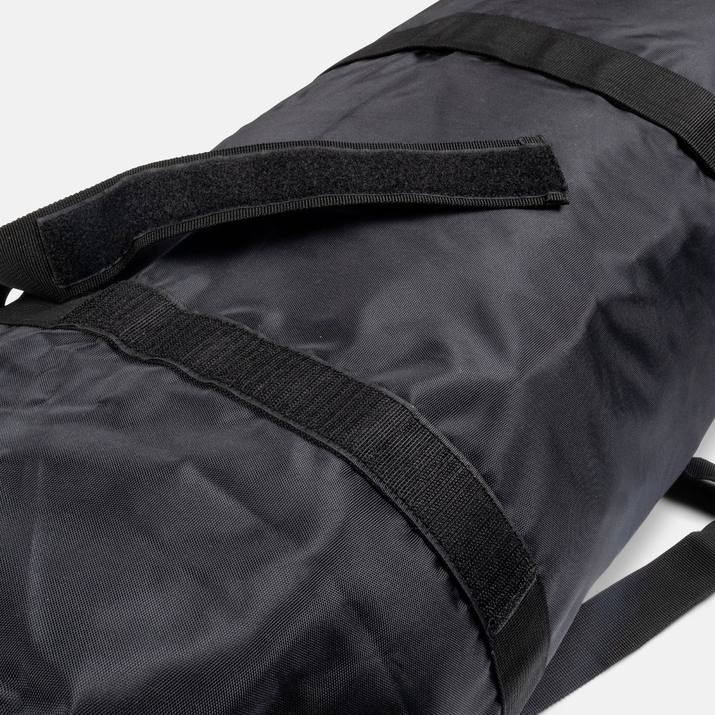 Black duffel bag with straps on a white background