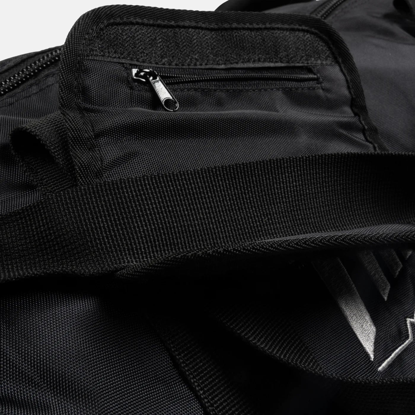 Close-up of a black duffel bag with a zipper pocket on a light gray background