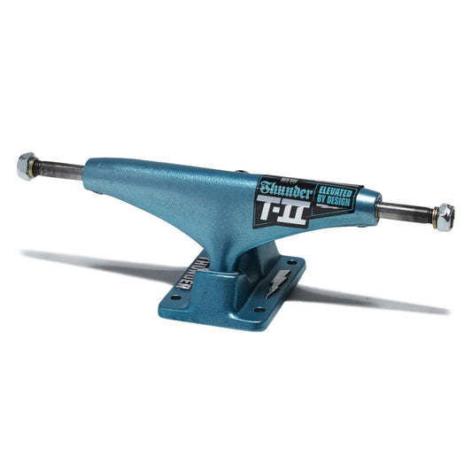 A metallic teal-blue skateboard truck with a black and white 'Blunder T-II' sticker, shown on a clean white background with a soft shadow.